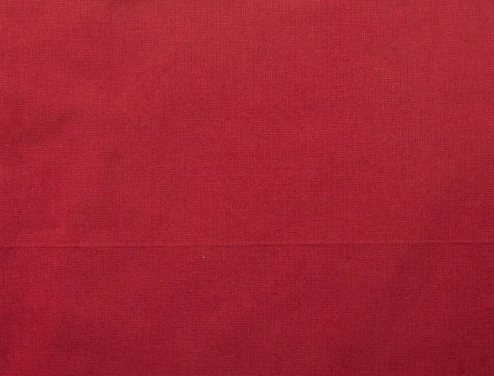 Close-up of the fabric on the red 140 g/m² cotton tote bag, showing the woven surface texture used for the body of the bag.