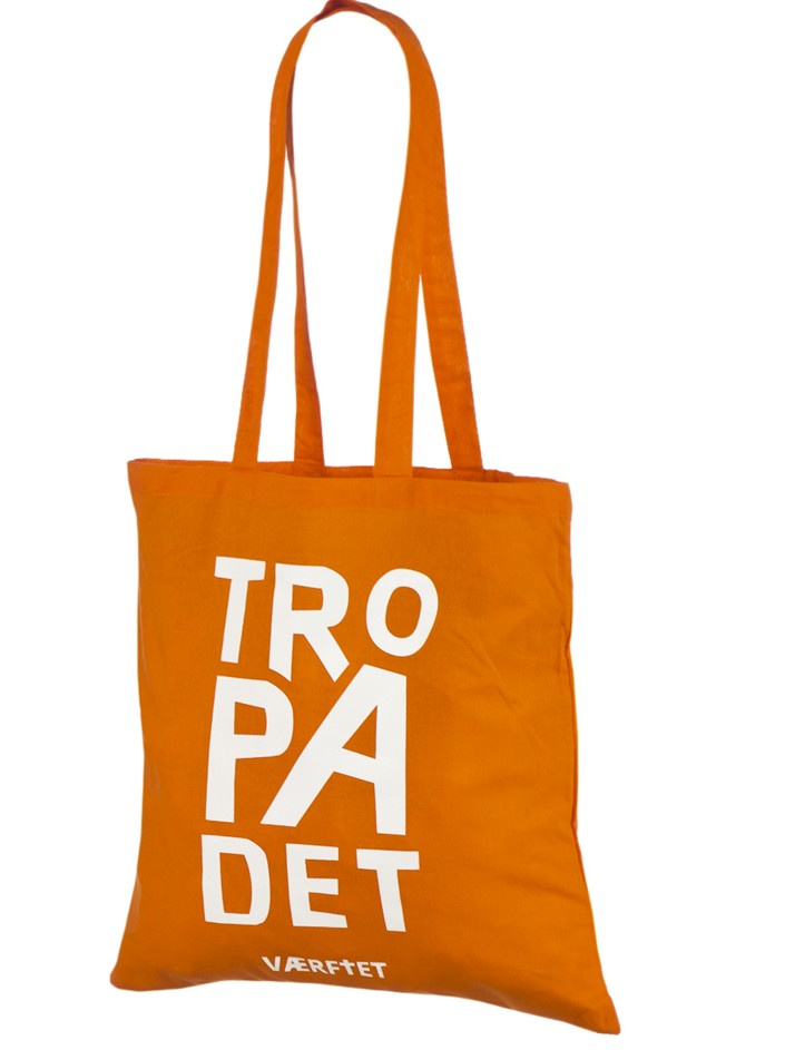 Tote bag en coton orange à anses longues, avec l'inscription TRO PÅ DET en grandes lettres blanches sur trois lignes et le nom VÆRFTET en petit en dessous.
